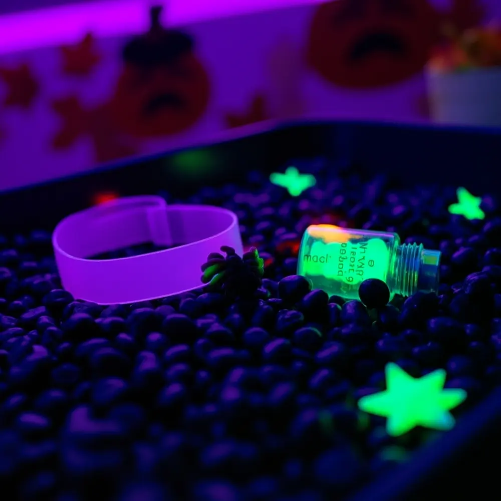 How to Create a Glow-in-the-Dark Sensory Bin 5 Side glow small view several the plastic water nestled glowing top its bracelet bottle a purple green sits on and an h3 items is of with image now 4 strong angled inside bin