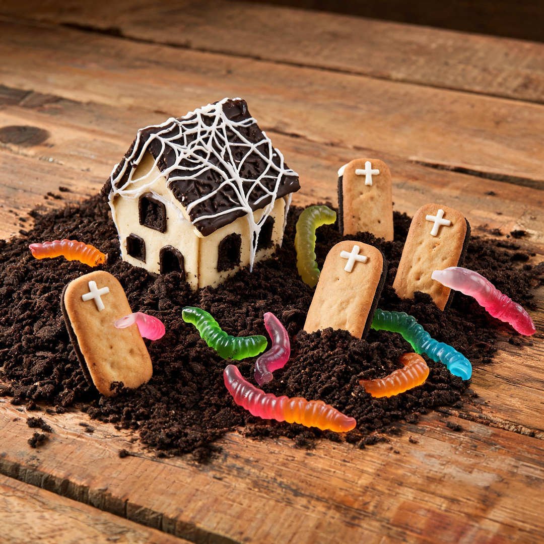 Gummy Worm Graveyard Base House - Spooky gingerbread house surrounded by crushed chocolate cookie dirt and neon gummy worms