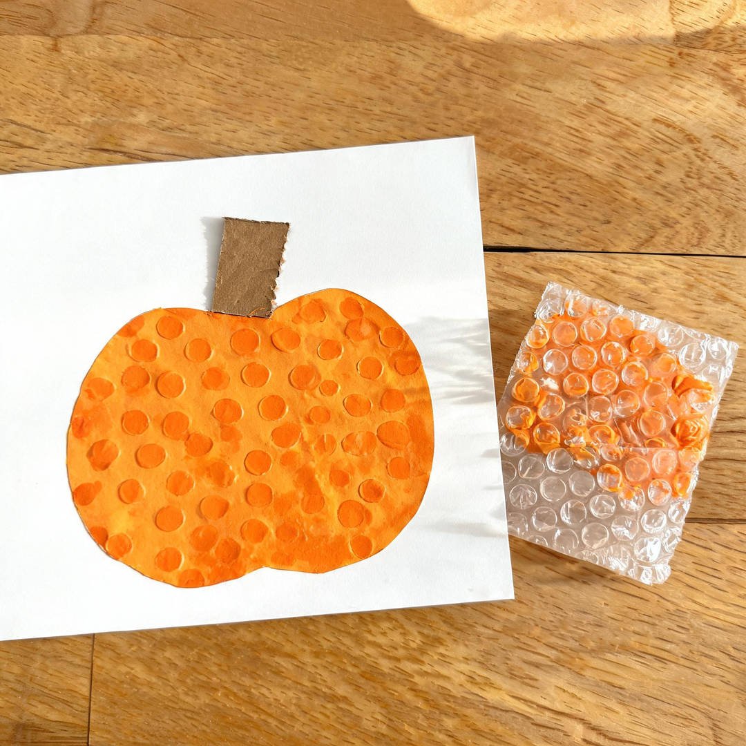 Bubble Wrap Stamped Pumpkin - Textured orange paint circles stamped with bubble wrap on white paper