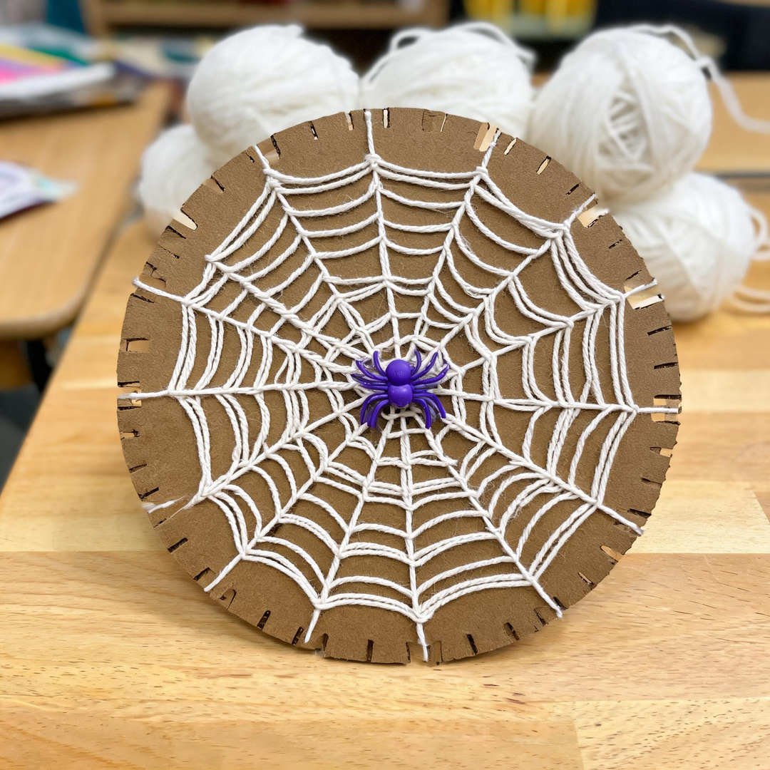 10 Easy Halloween Crafts for School (Grades 1-5) 6 Yarn-Wrapped Cardboard Spider Web - Notched cardboard circle woven with white yarn and a plastic spider